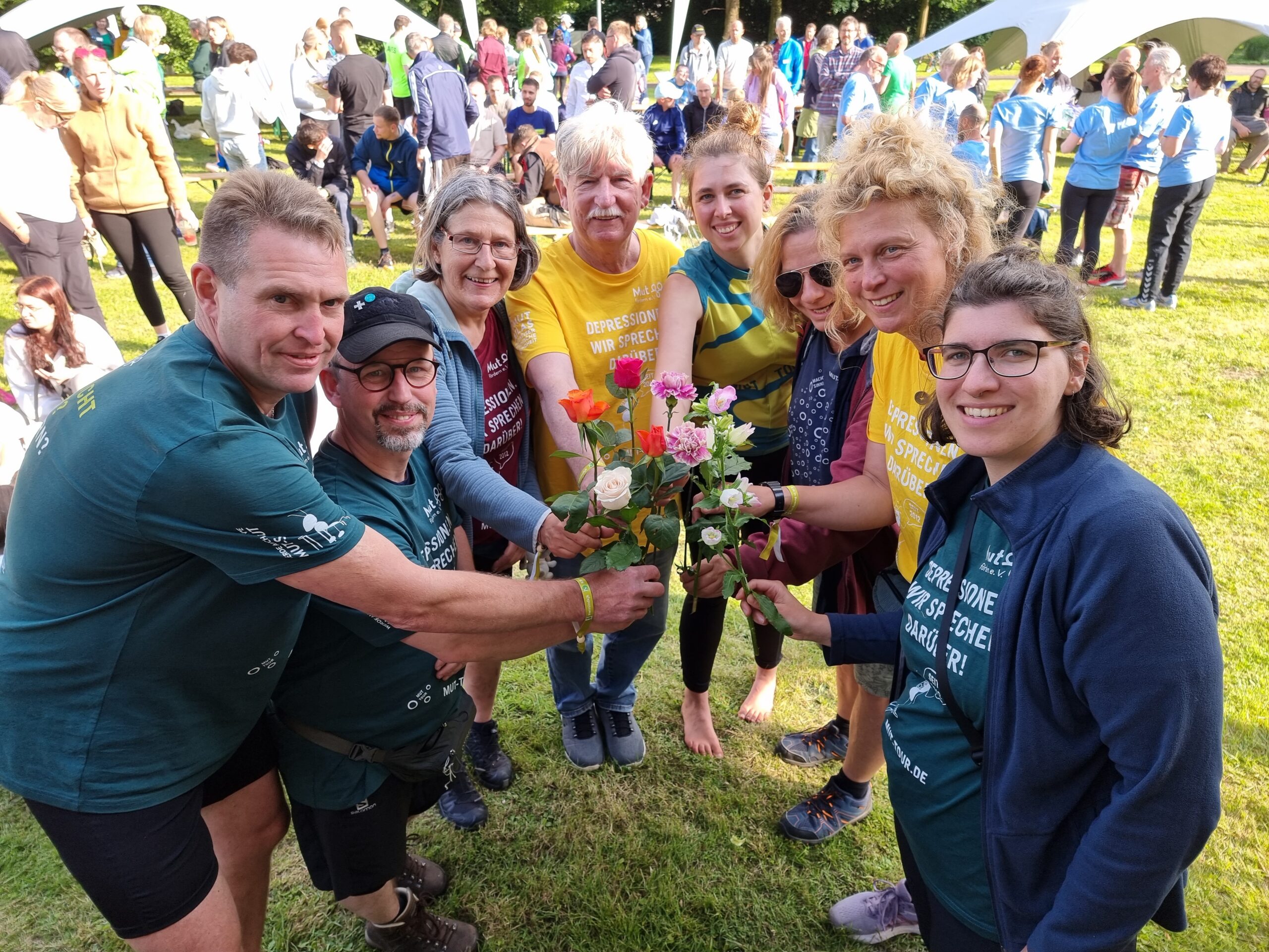 MUT-TOUR-Teilnehmende stehen im Kreis und halten Rosen zusammen zu einem Strauß
