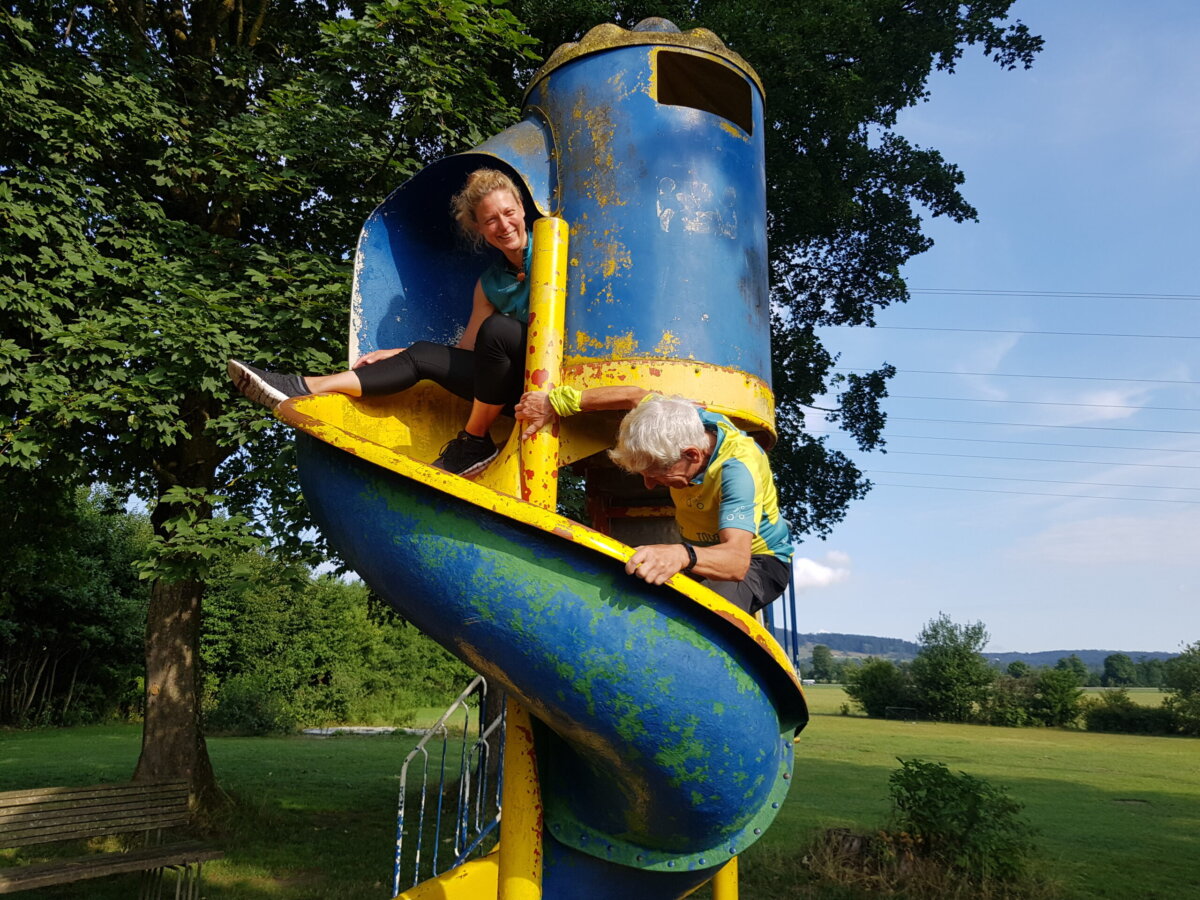 Frau und Mann auf rotgelbem spiralenförmigen Rutschturm