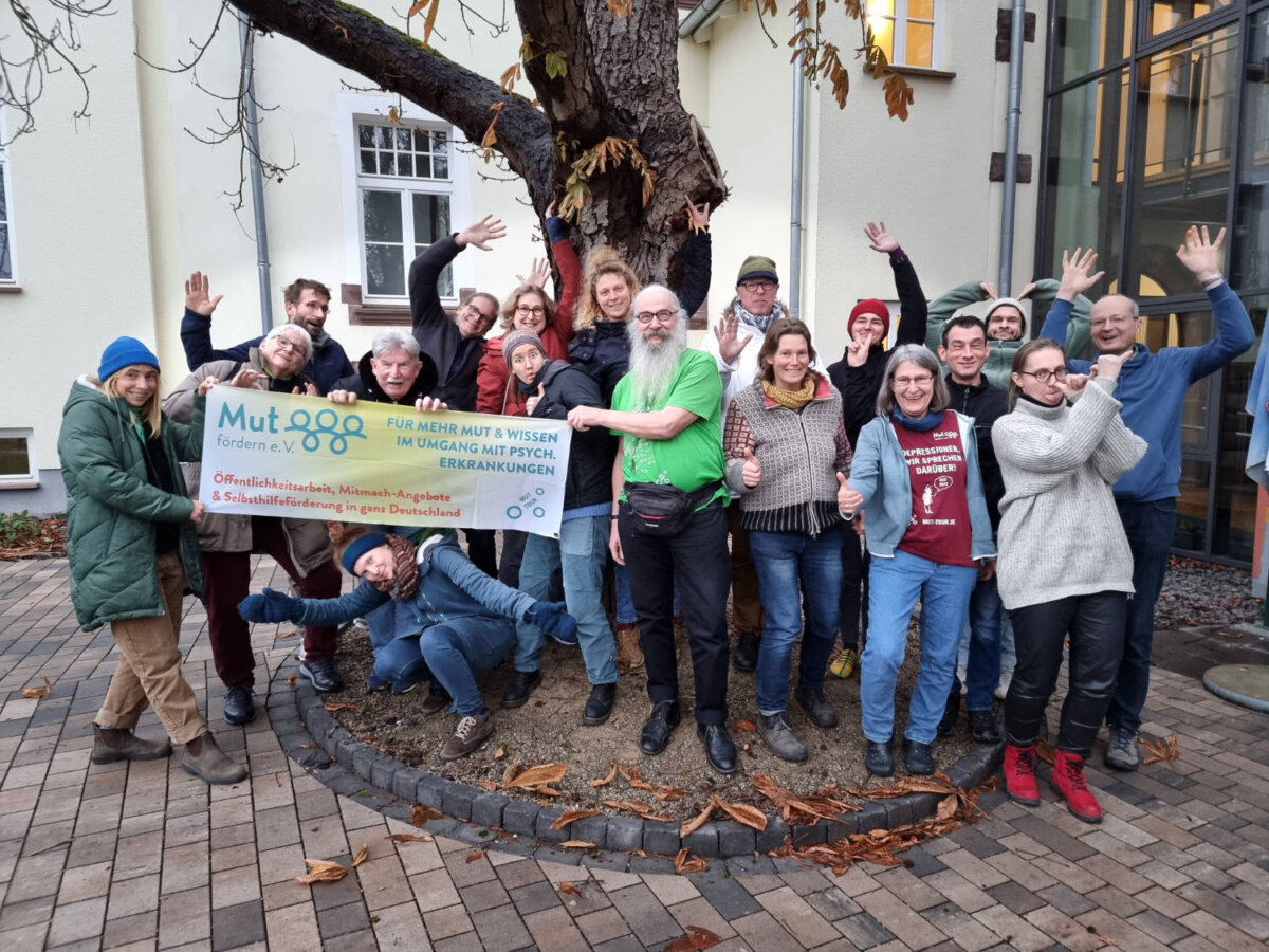 Eine große Gruppe Menschen steht mit dem MUT-TOUR Banner auf einem Platz in Oldenburg