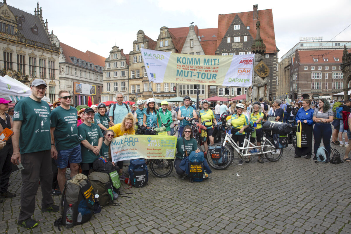 Menschen der MUT-TOUR mit Banner und Tshirts auf dem Bremer Marktplatz