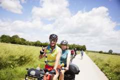 Zwei MUT-TOUR-Teilnehmende fahren auf einem Tandem auf einem sonnigen Feldweg (c) Sebastian Arlt