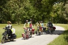 Mehrere MUT-TOUR-Teilnehmende auf Tandems und anderen Rädern fahren einen Feldweg entlang. (c) Sebastian Arlt