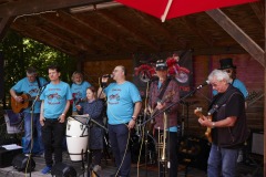 Mehrere Bandmitglieder mit blauen Tshirt stehen auf der Bühne und machen Musik (c) Sebastian Arlt